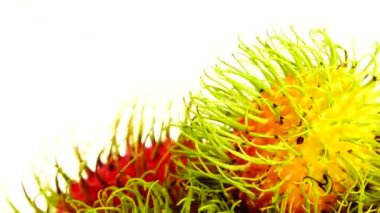 4K kırmızı freen renginde rambutan meyveler ve soyulmuş bir rambutan. Pikapta dönen beyaz arka planda izole edilmiş. Kapatın. Makro