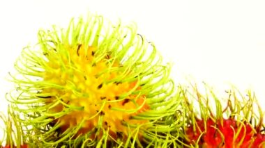 4K kırmızı freen renginde rambutan meyveler ve soyulmuş bir rambutan. Pikapta dönen beyaz arka planda izole edilmiş. Kapatın. Makro