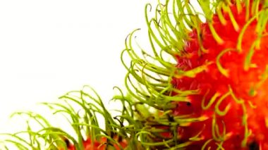 4K kırmızı freen renginde rambutan meyveler ve soyulmuş bir rambutan. Pikapta dönen beyaz arka planda izole edilmiş. Kapatın. Makro