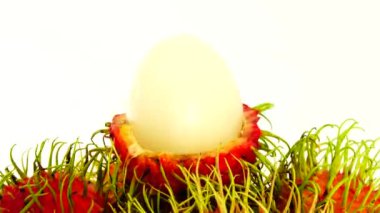 4K kırmızı freen renginde rambutan meyveler ve soyulmuş bir rambutan. Pikapta dönen beyaz arka planda izole edilmiş. Kapatın. Makro