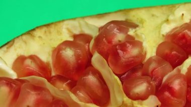 4K Organik sağlıklı kırmızı meyve yakın plan. Açık nar meyvesi yeşil arka planda döner. Nar tohumları.