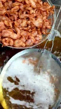 Kızarmış domuz eti parçaları kaynayan sıcak yağdan çekiliyor. Altın kahverengi doku, otantik Tayland sokak yemeklerini ayrıntılı olarak yakalıyor..