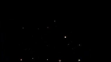 4 bin. Gerçek havai fişeklerin kusursuz döngü arka planında gece gökyüzünde Bokeh ışıkları olan altın havai fişekler. Parlak havai fişek gösterisi. Yeni yıl arifesinde havai fişekler birden fazla rengi kutluyor.