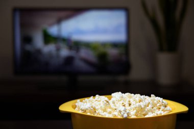 Televizyonun önünde patlamış mısır dolu sarı kase.