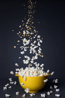 Siyah arka planda sarı bir kaseye düşen patlamış mısır. Dönüşüm süreci