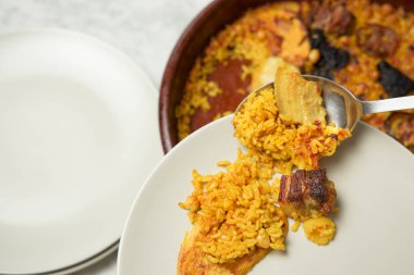 Adamın elleri bir kaşıkla tabakta fırında pilav servis ediyor. Valencia, İspanya