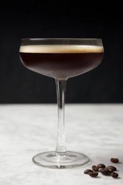 Mermer bir masada Espresso Martini 'nin ön görüntüsü. Kahve çekirdekleri dekorasyonu