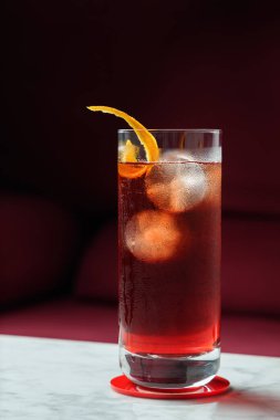 Portakallı Americano Kokteyli mermer bir masada. Arka plan olarak kırmızı kanepe. Ön görünüm