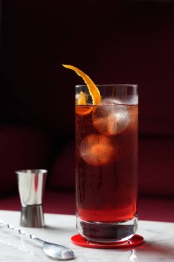 Portakallı Americano Kokteyli mermer bir masada. Arka plan olarak kırmızı kanepe. Ön görünüm