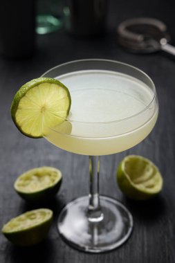 Klasik limon tekerli Daiquiri kokteyli. Siyah bir masanın üzerine sıkılmış limon.