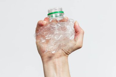 Adamın biri beyaz arka planda plastik bir şişeyi kırıyor.