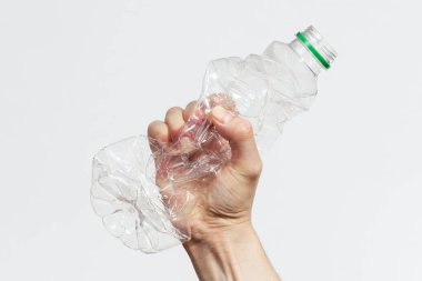 Adamın biri beyaz arka planda plastik bir şişeyi kırıyor.