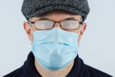 Cerrahi maske takan ve gözlük takan bir adam. Koronavirüs salgını sırasında koruyucu tedbir