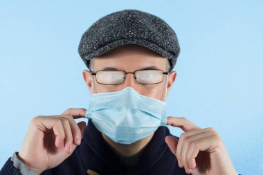 Cerrahi maske takan ve gözlük takan bir adam. Koronavirüs salgını sırasında koruyucu tedbir