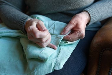 Yaşlı kadın evde dikiş dikmeye hazırlanıyor.