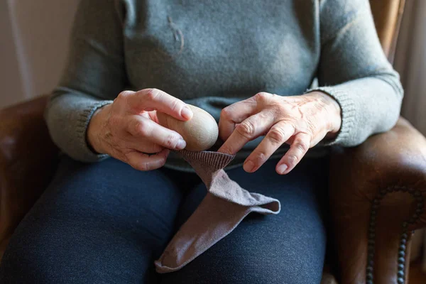 Old woman mending a sock at home