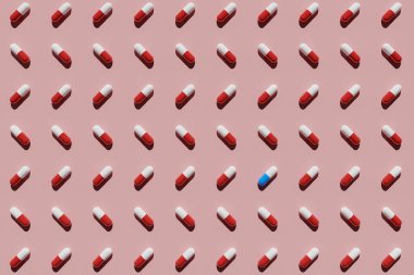Pembe arka planda kırmızı ve beyaz kapsüllerle çevrili mavi ve beyaz kapsül. 3B görüntüleme