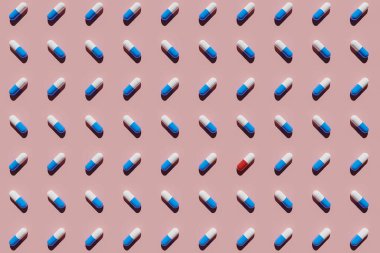 Kırmızı ve beyaz kapsüller pembe arka planda mavi ve beyaz kapsüllerle çevrili. 3B görüntüleme