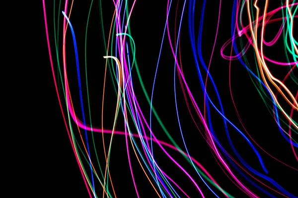 Multi color light painting photography, swirl and curve of blue, green and red light against a black background