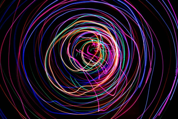 Multi color light painting photography, swirl and curve of blue, green and red light against a black background