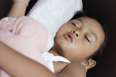 Sevimli küçük kız siyah koltukta en sevdiği oyuncakla uyuyor..