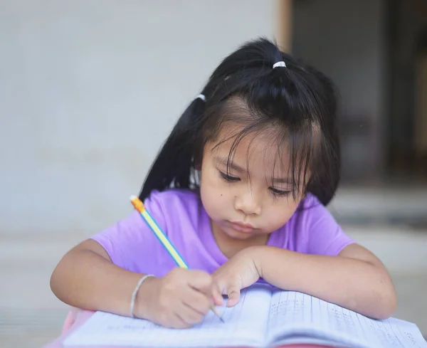 一个可爱的亚洲女孩白天在家里做作业 — 图库照片#