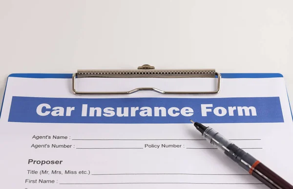 Car Insurance Claim Form or Auto Insurance Document and Pen and Clipboard on White Office Table