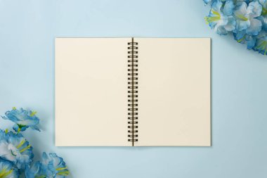 Üst Tablo Spiral Not Defteri veya Mavi Pastel Minimalist Arkaplanda Alt Sol ve Üst Sağ Köşedeki Çizgisiz Çerçeve ve Mavi Çiçekler Üzerine Çizgisiz Not Defteri
