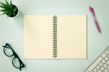 Top Table Spiral Notebook veya Spring Notebook Mockup in Unline Type on Center Frame and Red Pen and Glasses and Office Plant and Klavye on Blue Pastel Minimalist Arkaplan