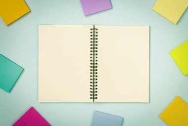Üst Tablo Spiral Not Defteri ya da Çizgisiz Orta Çerçeve ve Mavi Pastel Minimalist Arkaplan Üzerine Renkli Yapışkan Not Model