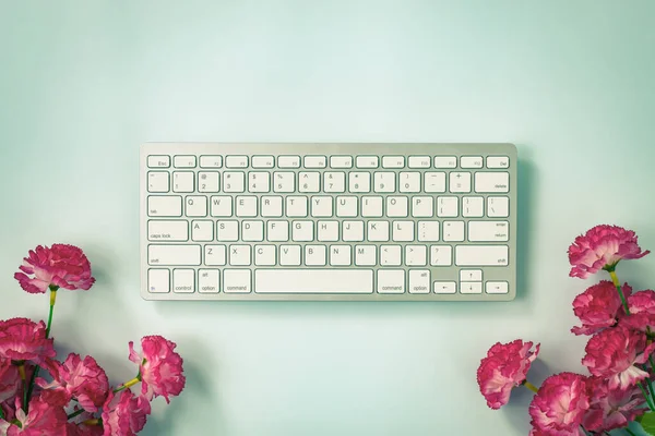 ホワイトポータブルコンピュータキーボードキーまたはキーボードボタンと赤の花の下に青のパステルミニマリストの背景でヴィンテージトーン — ストック写真