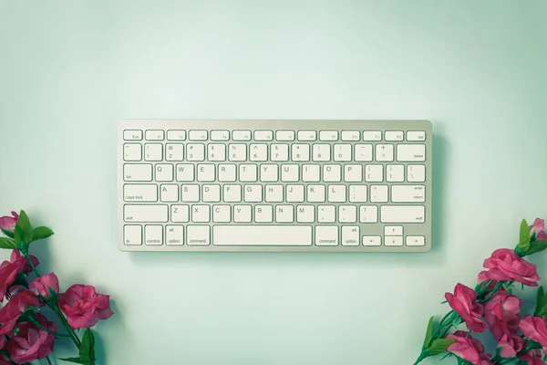 ホワイトポータブルコンピュータキーボードキーまたはキーボードボタンと青のパステルミニマリストの背景の下にバラの花ヴィンテージトーン — ストック写真