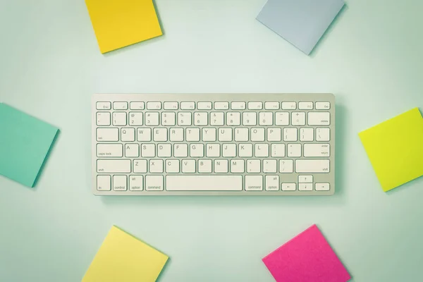 White Portable Computer Keyboard Keys or Keyboard Button and Colorful Stick Note or Note Pad on Blue Pastel Minimalist Background in Vintage Tone