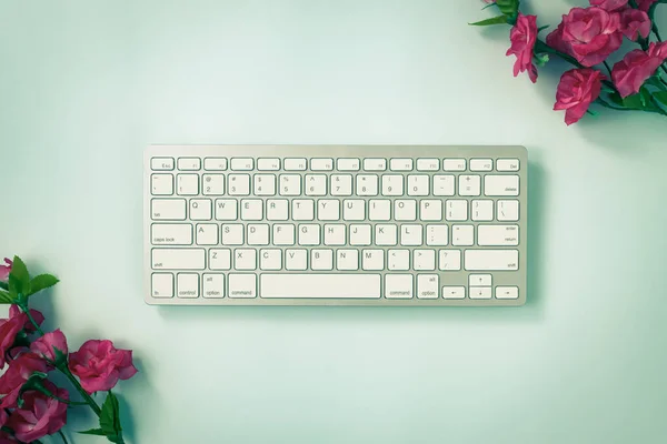 ホワイトポータブルコンピュータキーボードキーまたはキーボードボタンと青のパステルミニマリストの背景の右上と左上隅にバラの花ヴィンテージトーン — ストック写真
