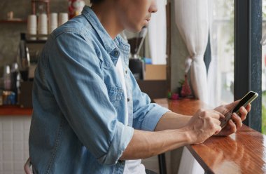 Doğru, Denim 'deki Asyalı Gündelik İş Adamı ya da Kafe' deki Akıllı Telefon 'daki Kot Tişört. Teknoloji ile çalışan sıradan bir iş adamı