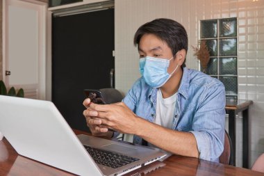 Zoom View Front, Asyalı Gündelik İş Adamı Denim 'de ya da Kotlu Gömlek Giyen Maskeli Adam Online Sohbet İçin Akıllı Telefon Kullanıyor. Covid 19 'daki Teknoloji Gelişigüzel İşadamı