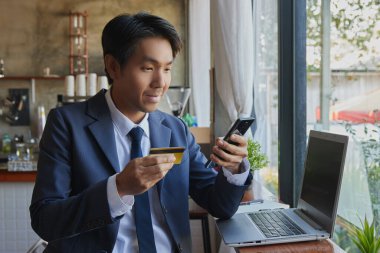 Ön Sağ Gülümseyen Asyalı İş Adamı Kafe Sahnesinde Çevrimiçi Ödeme için Akıllı Telefon Kullanıyor. Asyalı İşadamı Teknolojiyle Her Yerde Çalışıyor