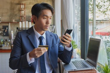 Ön Sağ Asyalı Takım Elbiseli İşadamı Kafe Sahnesinde Çevrimiçi Ödeme İçin Akıllı Telefon Kullanıyor. Asyalı İşadamı Teknolojiyle Her Yerde Çalışıyor