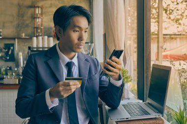 Ön Sağ Asyalı Takım Elbiseli İşadamı Kafe Sahnesinde Çevrimiçi Ödeme İçin Akıllı Telefon Kullanıyor. Asyalı İşadamı Vintage Tone Teknolojisi ile Her Yerde Çalışıyor