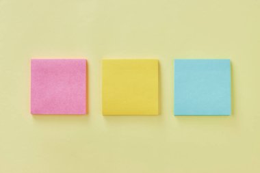 Üst Görünüm veya Düz Yatır 3 Renkli Not Defteri veya Not Defteri Pembe, Sarı, Turkuaz Ofis Masasında veya Ofis Masasında. Pastel Sarı Minimalist Arkaplan Ofis Malzemeleri