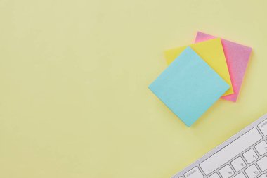 Üst Görünüm 3 Yapışkan Not ve Klavye Ofis Masasında veya Ofis Masası Arkaplanında. Sarı Minimalist Arkaplan Ofis Malzemeleri