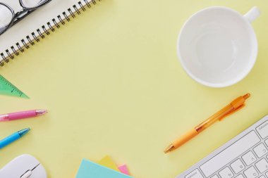 Top View ya da Flat Lay Modern Office Masası veya Klavye, Pen, Stick Nota, Fare, Cetvel, Not Defteri, Gözlük, Kahve Kupası olarak Kırtasiye Masası. Sarı Minimalist Çalışma Alanı Arkaplanı