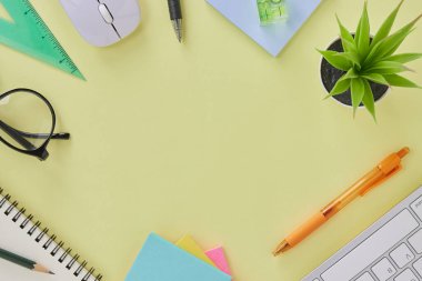 Top View veya Flat Lay Modern Ofis Masası veya Ofis Malzemeleri Klavye, Kalem, Not Defteri, Kalem, Gözlük, Fare, Su Seviyesi, Bitki. Sarı Minimalist Çalışma Alanı Arkaplanı