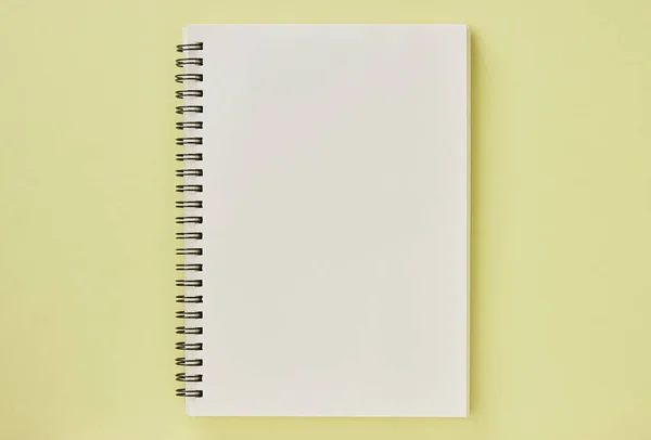 Spiral Notebook or Spring Notebook in Unlined Type on Pastel Yellow Minimalist Background. Spiral Notebook Mock up on Center Frame