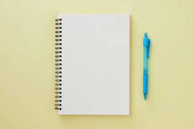 Spiral Notebook veya Spring Notebook in Unline Type and Blue Pen on Pastel Yellow Minimalist Arkaplan. Spiral Not Defteri Orta Çerçeve 'ye uydur