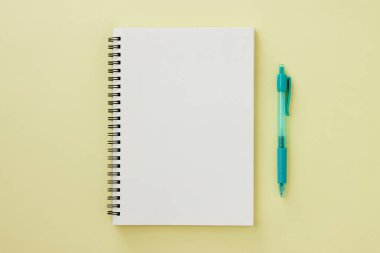 Spiral Notebook veya Spring Notebook in Unline Type and Green Pen on Pastel Yellow Minimalist Arkaplan. Spiral Not Defteri Orta Çerçeve 'ye uydur