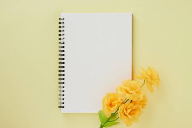 Spiral Not Defteri ya da Pastel Sarı Minimalist Arkaplan 'da Çizgisiz Tür ve Turuncu Çiçek ile Bahar Defteri. Spiral Not Defteri Orta Çerçeve 'ye uydur