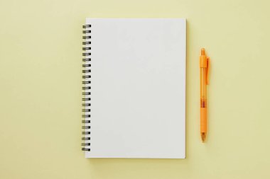 Spiral Notebook veya Spring Notebook in Unline Type and Orange Pen on Pastel Yellow Minimalist Arkaplan. Spiral Not Defteri Orta Çerçeve 'ye uydur