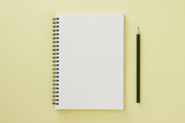 Spiral Notebook veya Spring Notebook in Unline Type and kalem on Pastel Yellow Minimalist Arkaplan. Spiral Not Defteri Orta Çerçeve 'ye uydur