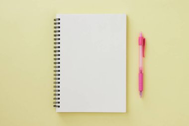 Spiral Notebook veya Spring Notebook in Unline Type and Pink Pen on Pastel Yellow Minimalist Arkaplan. Spiral Not Defteri Orta Çerçeve 'ye uydur
